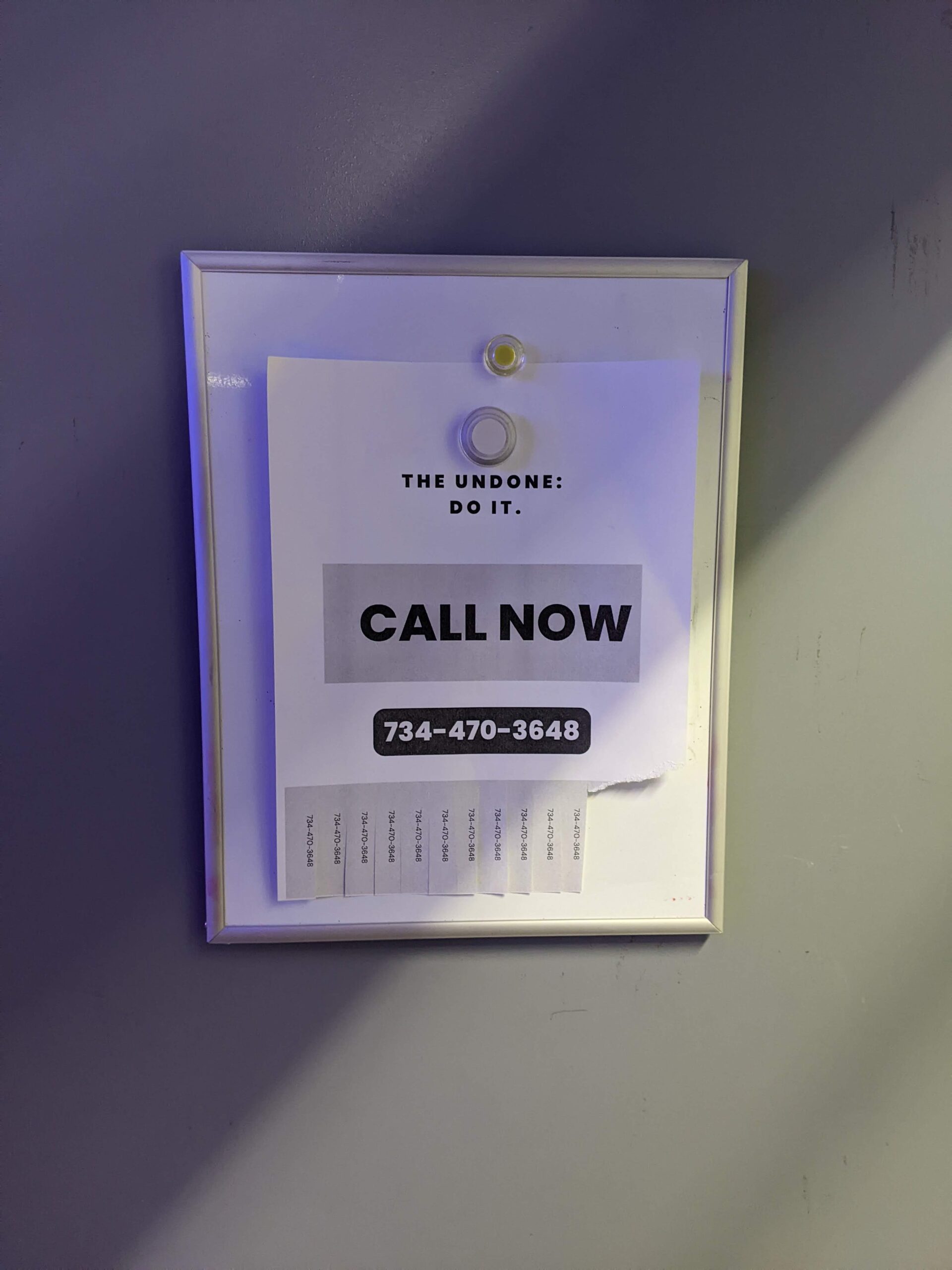 Paper with words "Call Now" and number pinned on canvas